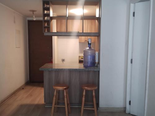 a kitchen with two stools and a bottle of water on a counter at Arriendo de Dpto por día o mensual céntrico in Santiago