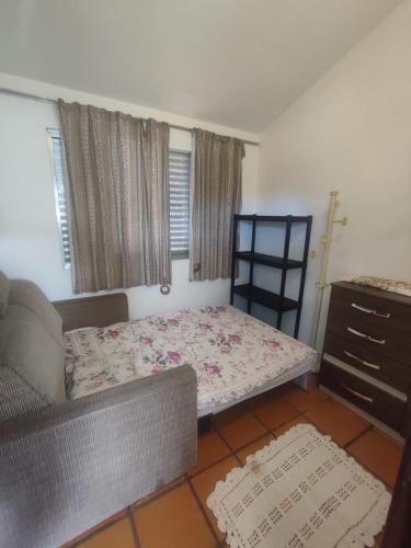 uma cama num quarto com um sofá e uma cómoda em Suite Daniela em Florianópolis