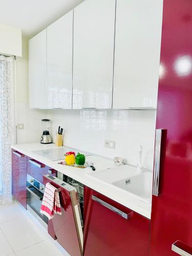 een keuken met witte toonbanken en rode kasten bij Spacious apartment in the center of Nice near the sea in Nice