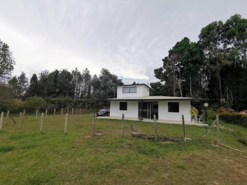 a white house in the middle of a field at Hermosa finca a 5 minutos aeropuerto in Guarne