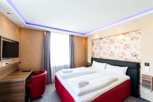 a hotel room with a bed and a red chair at Stay-Inn Bielefeld Zentrum in Bielefeld