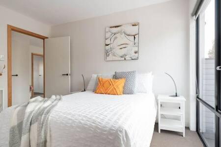 Un dormitorio con una cama blanca con almohadas naranjas. en CBD Apartment with WiFi & Parking, en Launceston