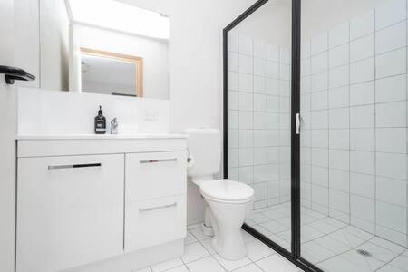 a white bathroom with a toilet and a shower at CBD Apartment with WiFi & Parking in Launceston