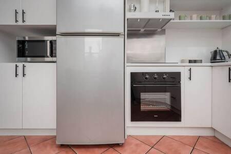 a kitchen with white cabinets and an oven at CBD Apartment with WiFi & Parking in Launceston