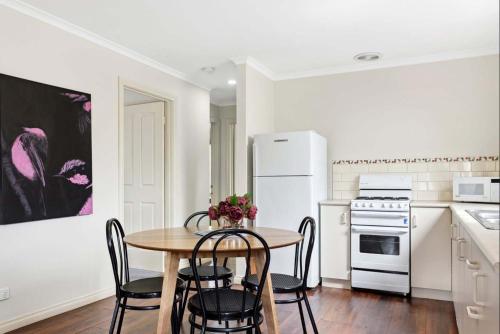 a kitchen with a table and chairs and a refrigerator at Birdie Daylesford in Daylesford