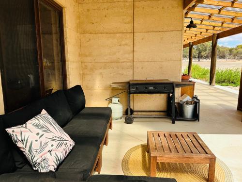 a patio with a black couch and a grill at Rammed Earth Retreat in Wagin