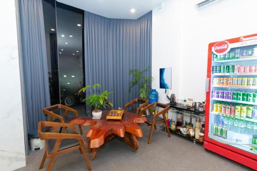 Gems Hotel - Khách sạn Trảng Bàng في Trảng Bàng: غرفة مع طاولة وكراسي وثلاجة للشرب