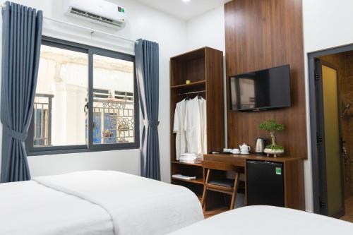 a bedroom with two beds and a tv and a window at Gems Hotel - Khách sạn Trảng Bàng in Trảng Bàng