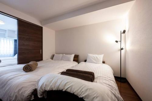 a bedroom with two beds and a large window at Shizuk+O Stay in Sapporo