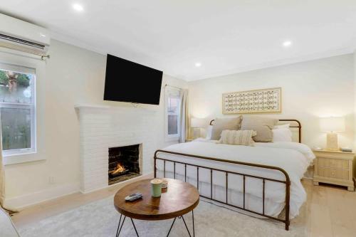 a white bedroom with a bed and a fireplace at Charming Cottage on Croton #1 in West Palm Beach