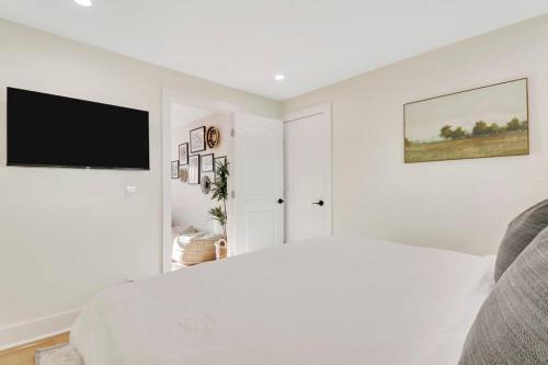 a white room with a bed and a flat screen tv at Cottage on Croton Way # 2 in West Palm Beach