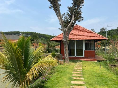 una pequeña casa roja con un árbol delante en Dak Nguyen Homestay & Farm 2, en Gia Nghĩa