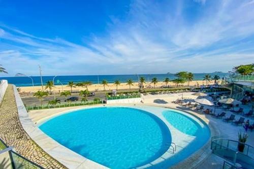 uma grande piscina azul ao lado de uma praia em Suíte Luxo São Conrado - Hotel Nacional no Rio de Janeiro