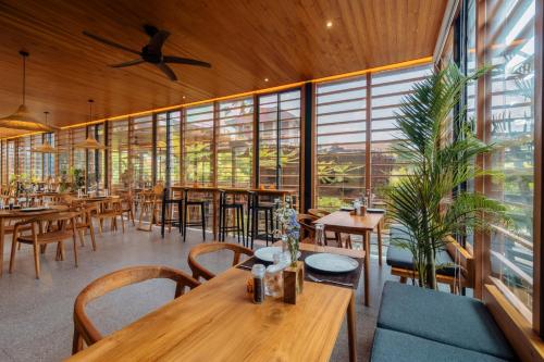 ein Restaurant mit Tischen und Stühlen und großen Fenstern in der Unterkunft Canggu Cabana Resort By Ini Vie Hospitality in Canggu