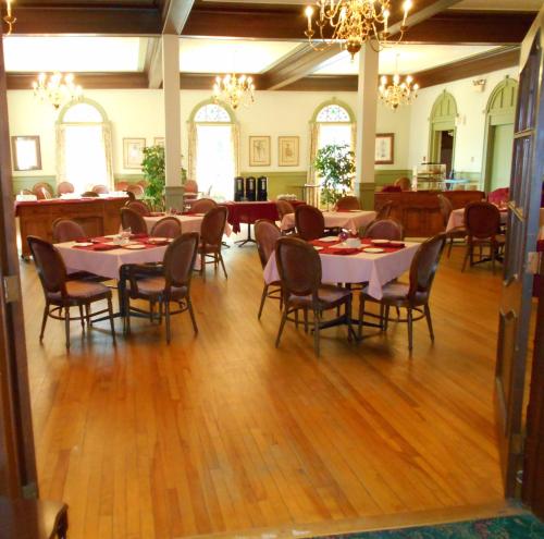 a dining hall with tables and chairs and chandeliers at Braeside Country Inn in Pictou