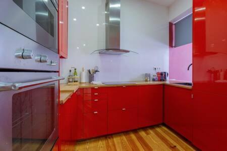 a red kitchen with red cabinets and a stove at Old Town Chiado Balcony AirCon by LD Apartments in Lisbon