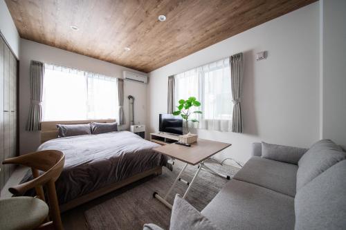 a bedroom with a bed and a couch and a table at ASCEND【2min from Asahikawa sta】 in Asahikawa