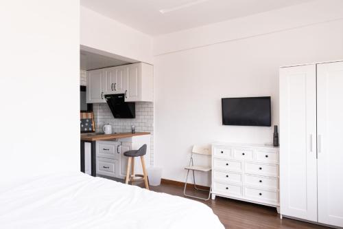 a white bedroom with a white bed and a kitchen at 1930 French Minimalist Apartment in Shanghai