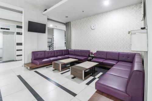 a living room with purple couches and a tv at The Edge by Lia in Cimindi-hilir