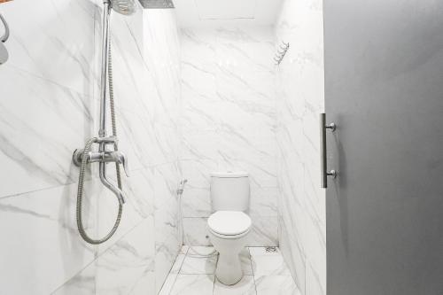 a white bathroom with a shower and a toilet at The Edge by Lia in Cimindi-hilir