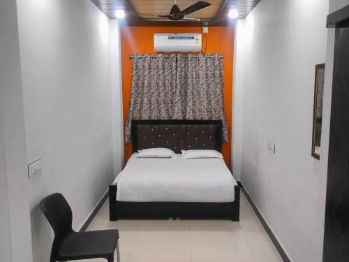 een kleine slaapkamer met een bed en een stoel bij SHIV SNEH HOME STAYS in Ujjain