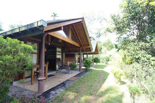a house with a covered porch and a garden at 360 Rainforest in Deniyaya