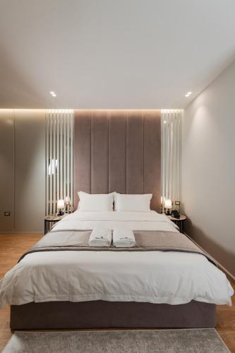 a bedroom with a large white bed with two tables at Troci Hotel in Tirana