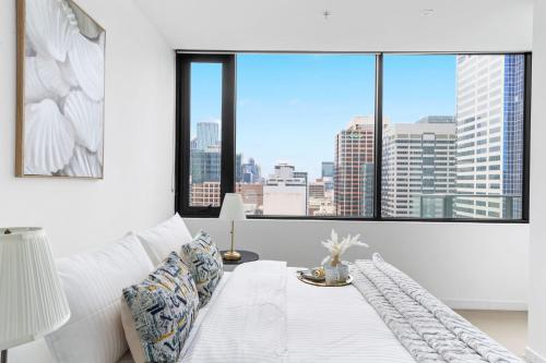 een witte slaapkamer met uitzicht op de stad bij Modern 2BR Apt Next to Southern Cross FREE Parking in Melbourne