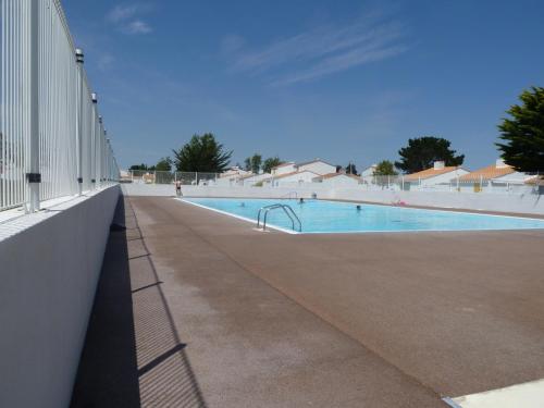 - une piscine à côté d'un bâtiment blanc dans l'établissement Maison de Vacances avec Piscine Chauffée, Tennis et Proximité Mer à Bretignolles-sur-Mer - FR-1-231-309, à Bretignolles-sur-Mer