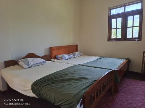 2 Einzelbetten in einem Schlafzimmer mit Fenster in der Unterkunft NSM Wedding hall and guest room 