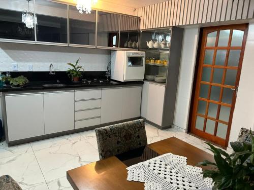 cocina con armarios blancos, mesa y microondas en casa da Gilvana en São Gabriel