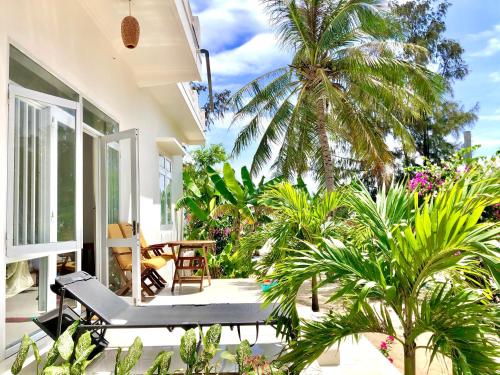 a porch with a palm tree and a bench at Robinson Beach Bungalow in Vinh Hoa