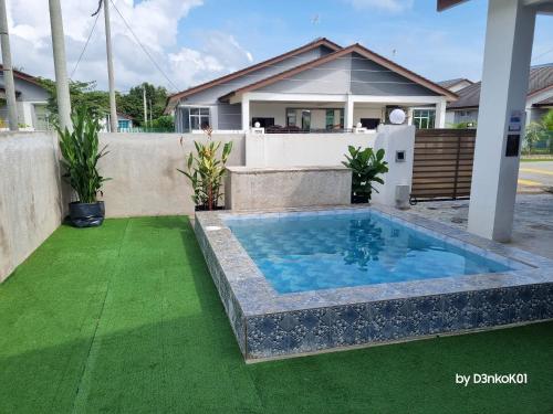 a swimming pool in the backyard of a house with green grass at AfiRA Homestay Cherating in Kuantan