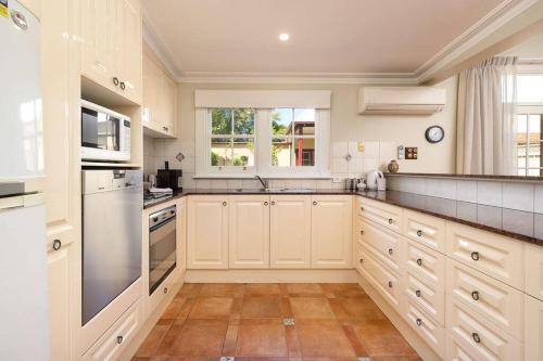 een grote keuken met witte kasten en een wastafel bij Porters Cottage Oasis in Albury