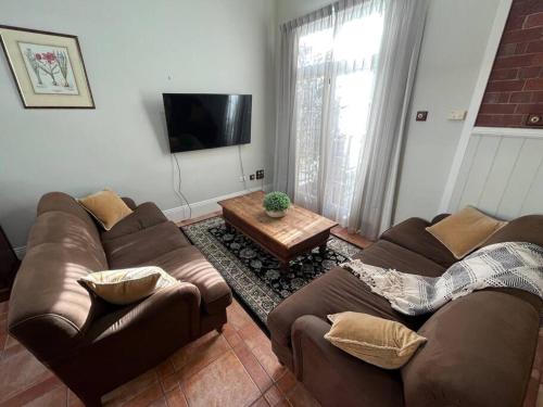 a living room with two couches and a coffee table at Porters Cottage Oasis in Albury