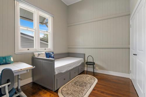 a bedroom with a bed and a desk and a window at Heritage Queenslander Gem - Families & Groups - Minutes to CBD & South Brisbane in Brisbane
