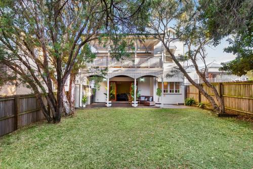 a white house with a fence and a yard at Heritage Queenslander Gem - Families & Groups - Minutes to CBD & South Brisbane in Brisbane