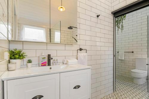 a white bathroom with a sink and a toilet at Heritage Queenslander Gem - Families & Groups - Minutes to CBD & South Brisbane in Brisbane