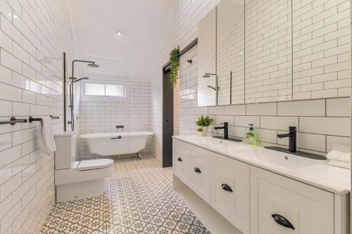 a bathroom with two sinks and a tub and a toilet at Unique Character Queenslander Home! Just Minutes to CBD & South Brisbane in Brisbane