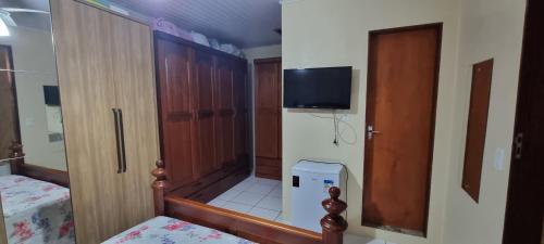 Habitación pequeña con armario y TV en la pared. en casa da Gilvana en São Gabriel
