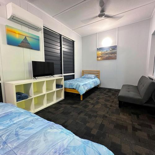Unit 2 Golden Sands Retreat في Wagait Beach: غرفة بسرير وتلفزيون وأريكة
