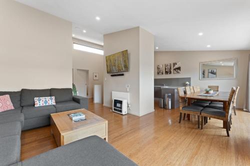 a living room with a couch and a table at Khione 1 - 3BR Modern Townhouse l Mountain Views l WiFi l BBQ l Smart TV in Jindabyne