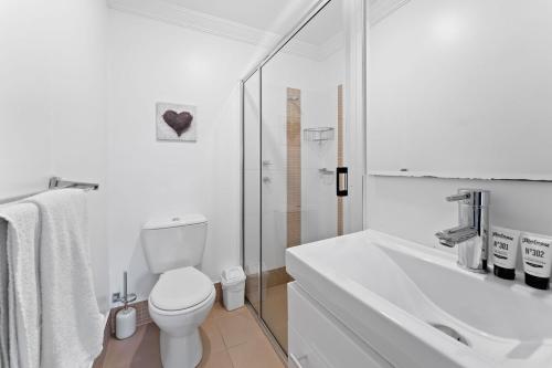 a white bathroom with a toilet and a sink at Khione 1 Modern spacious with views towards Lake Jindabyne the mountains beyond in Jindabyne