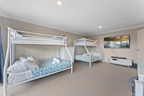 a bedroom with two bunk beds and a desk at Khione 1 Modern spacious with views towards Lake Jindabyne the mountains beyond in Jindabyne