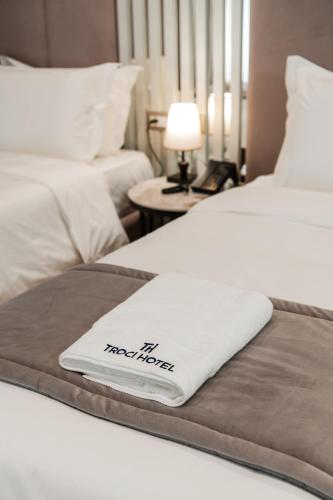 a hotel room with two beds with a towel on the bed at Troci Hotel in Tirana