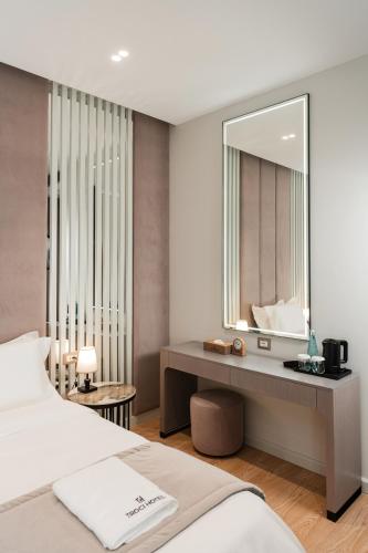 a bedroom with a bed and a vanity with a mirror at Troci Hotel in Tirana