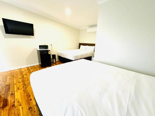 a bedroom with two beds and a flat screen tv at Seven Inn in Wagga Wagga