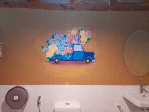 a bathroom with a painting of a car with flowers on the wall at Lazy Hut in Ko Phayam