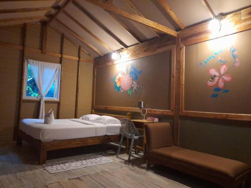 a bedroom with a bed and a chair in a room at Lazy Hut in Ko Phayam
