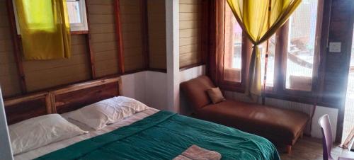 a bedroom with a bed and a chair and a window at Lazy Hut in Ko Phayam